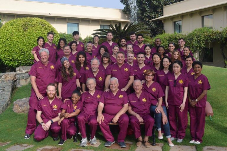 A large Ayuda team in maroon scrubs gathered outdoors