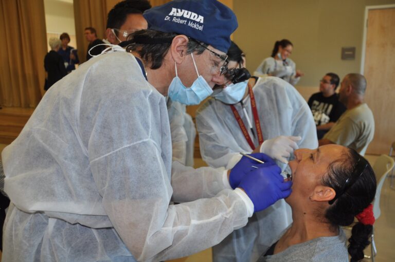 A volunteer dentist in mask and gloves treating a patient