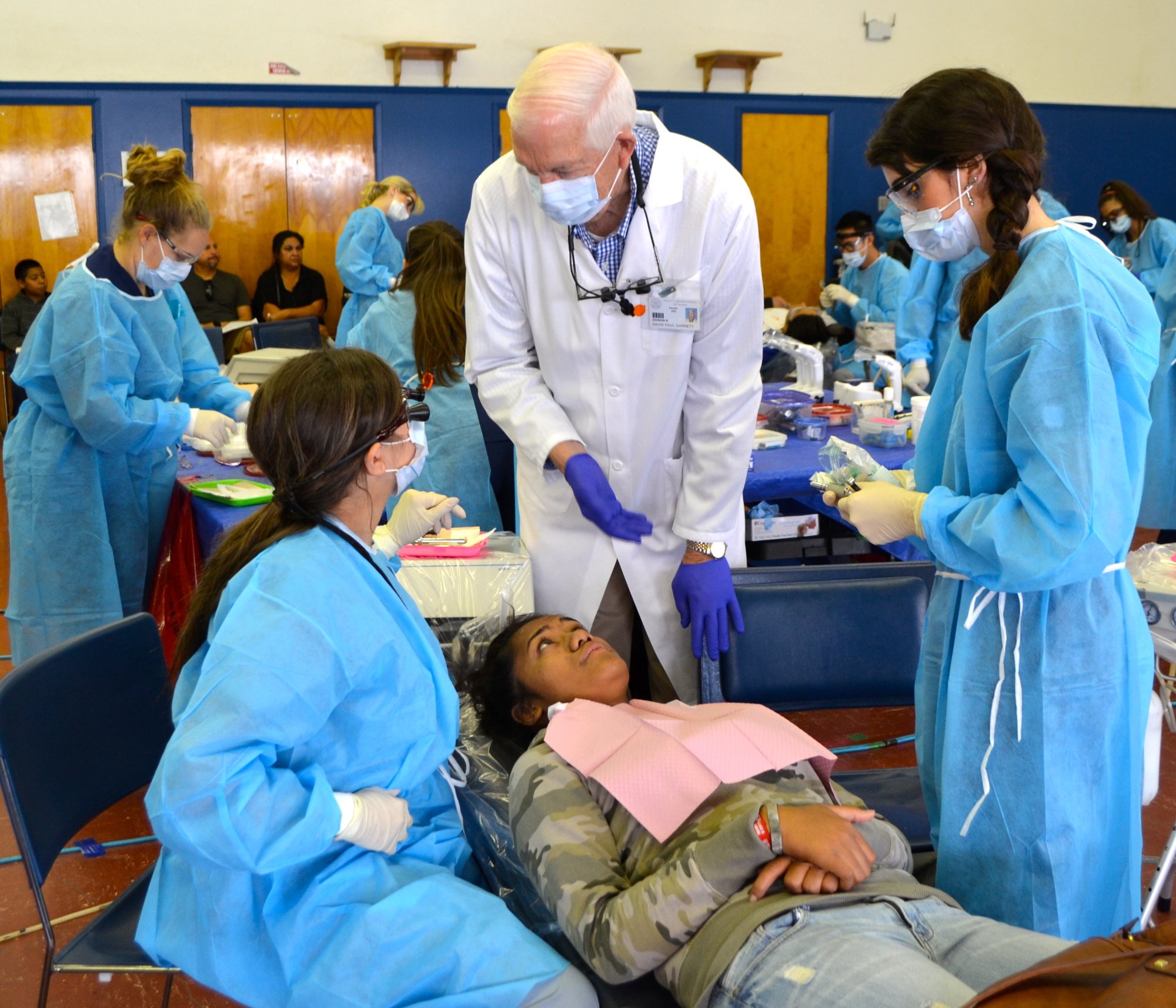 An Ayuda dentist treating a young patient while volunteers assist