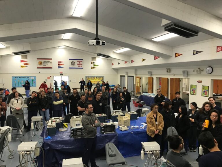 A free dental clinic set up with rows of chairs in a large hall