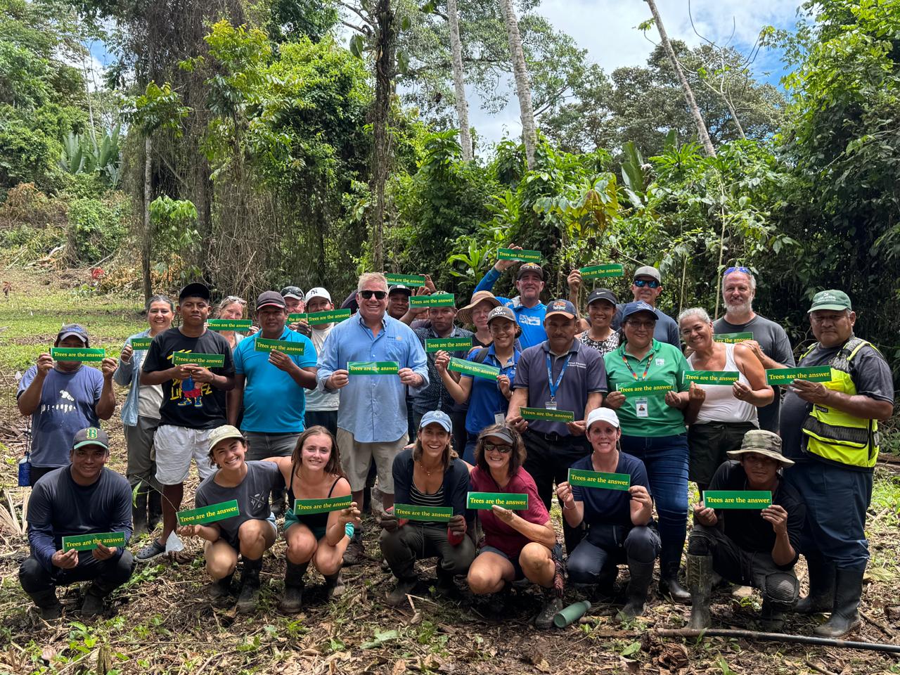 Ayuda and Rotary volunteers with local partners holding Trees are the answer signs at a tree planting in Panama