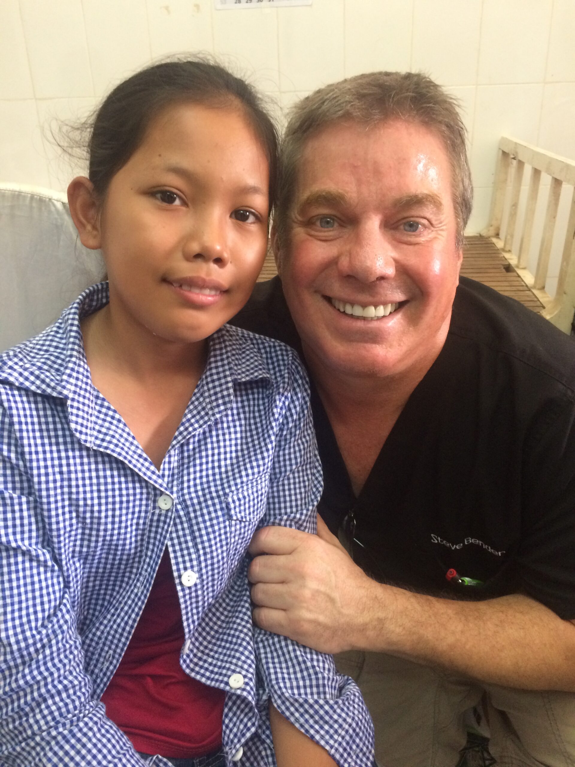 The same girl smiling beside Steve Bender after her treatment